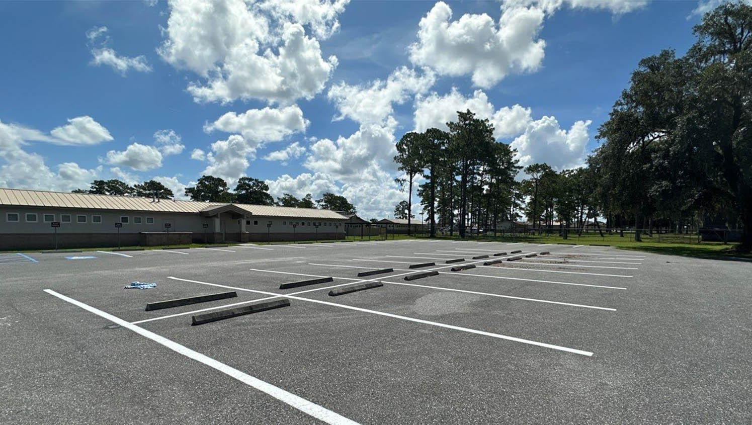 Cars entering Baptist Health Training Complex parking lot in Miami Gardens with fans walking toward facility carrying Dolphins gear on sunny morning